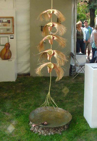 rain chain made from tablet-woven copper and brass wire with hammered brass basin